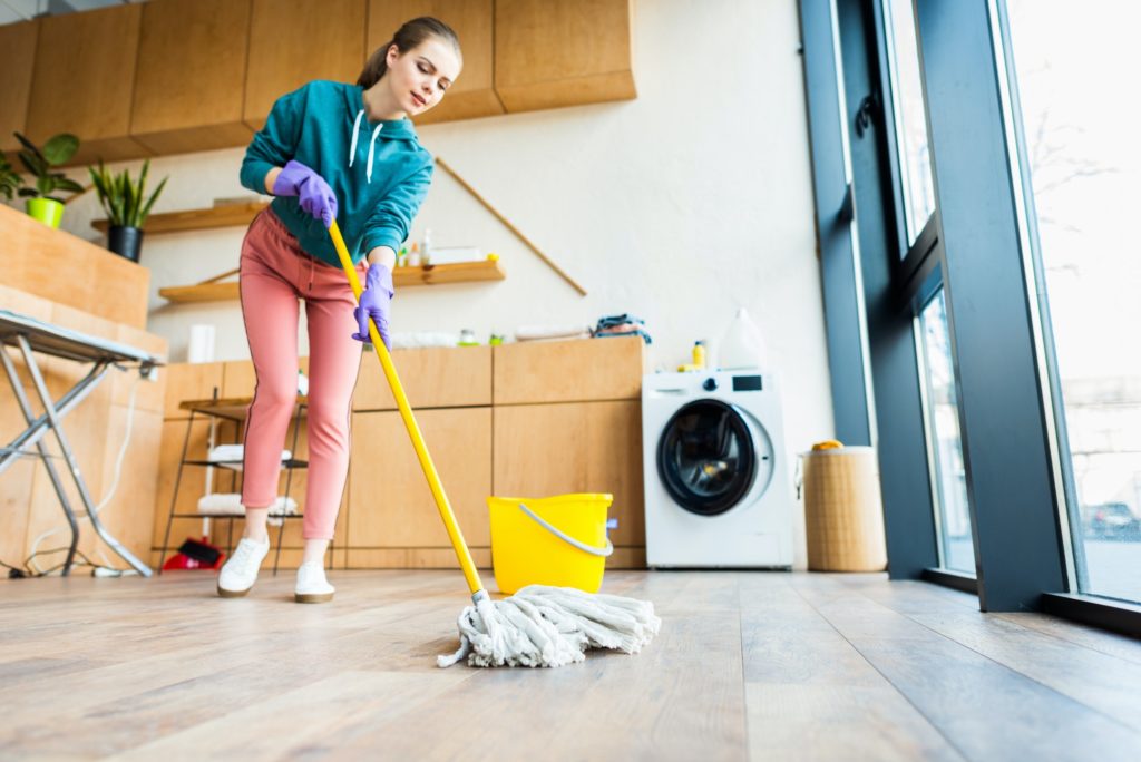 low angle view of young woman cleaning home with mop